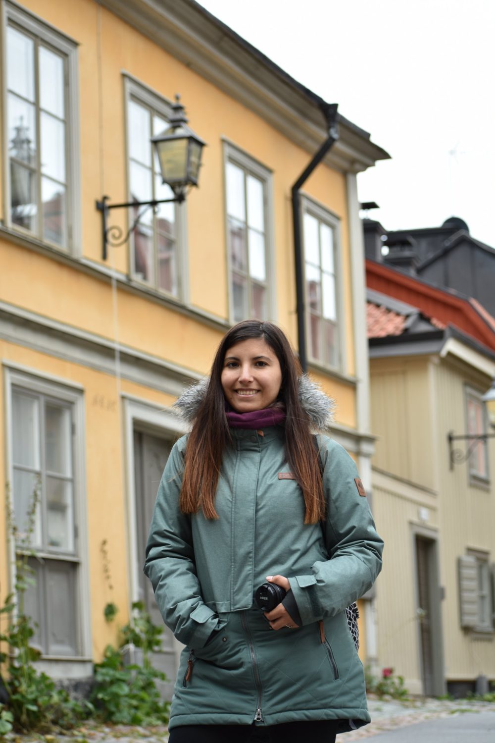 Ana Clara Muñoz sonriendo con su cámara en una calle de casas antiguas